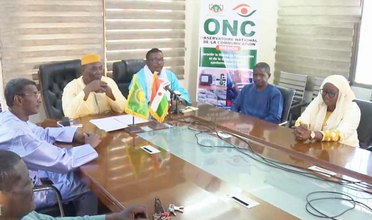 Salle de presse avec écrans affichant des logos de médias suspendus au Niger